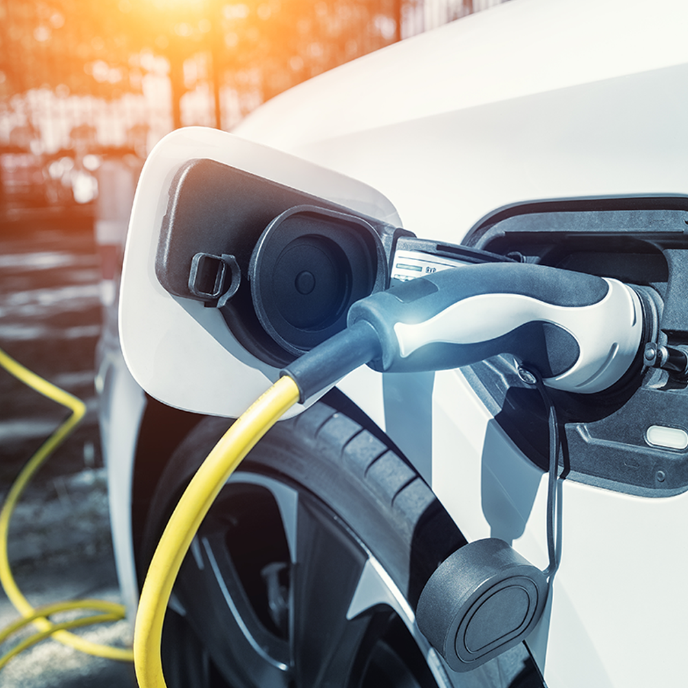 Electric vehicle charging with a yellow cable connected to a white EV – representing fast and reliable EV charging solutions available from Evergy in Thame.